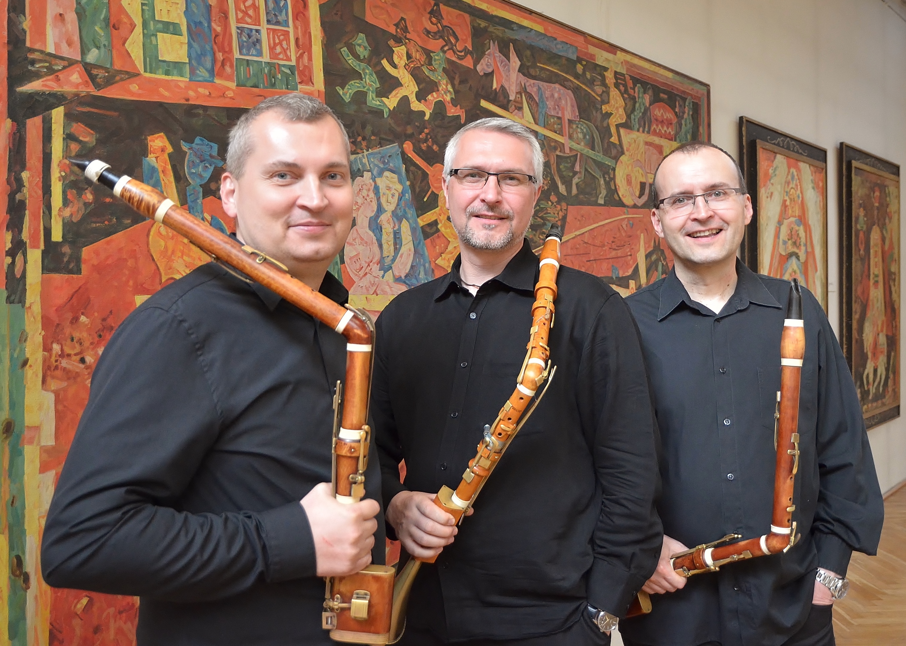 trzech muzyków z insturmentami w czarnych koszulach