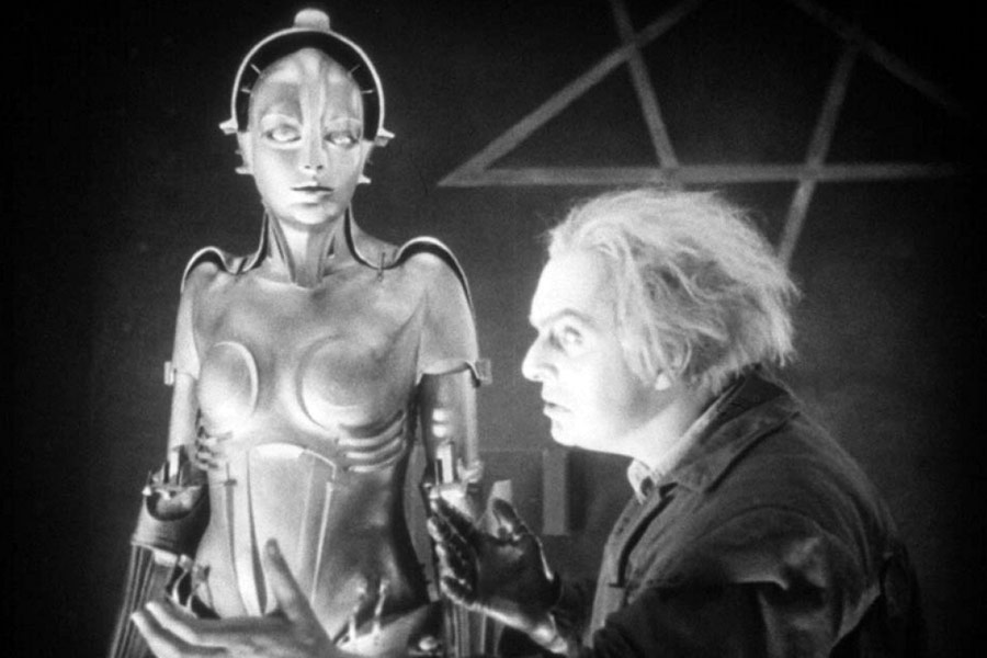 kadr z filmu przedstawiający futurystycznie ubraną kobietę i leciwego mężczyznę