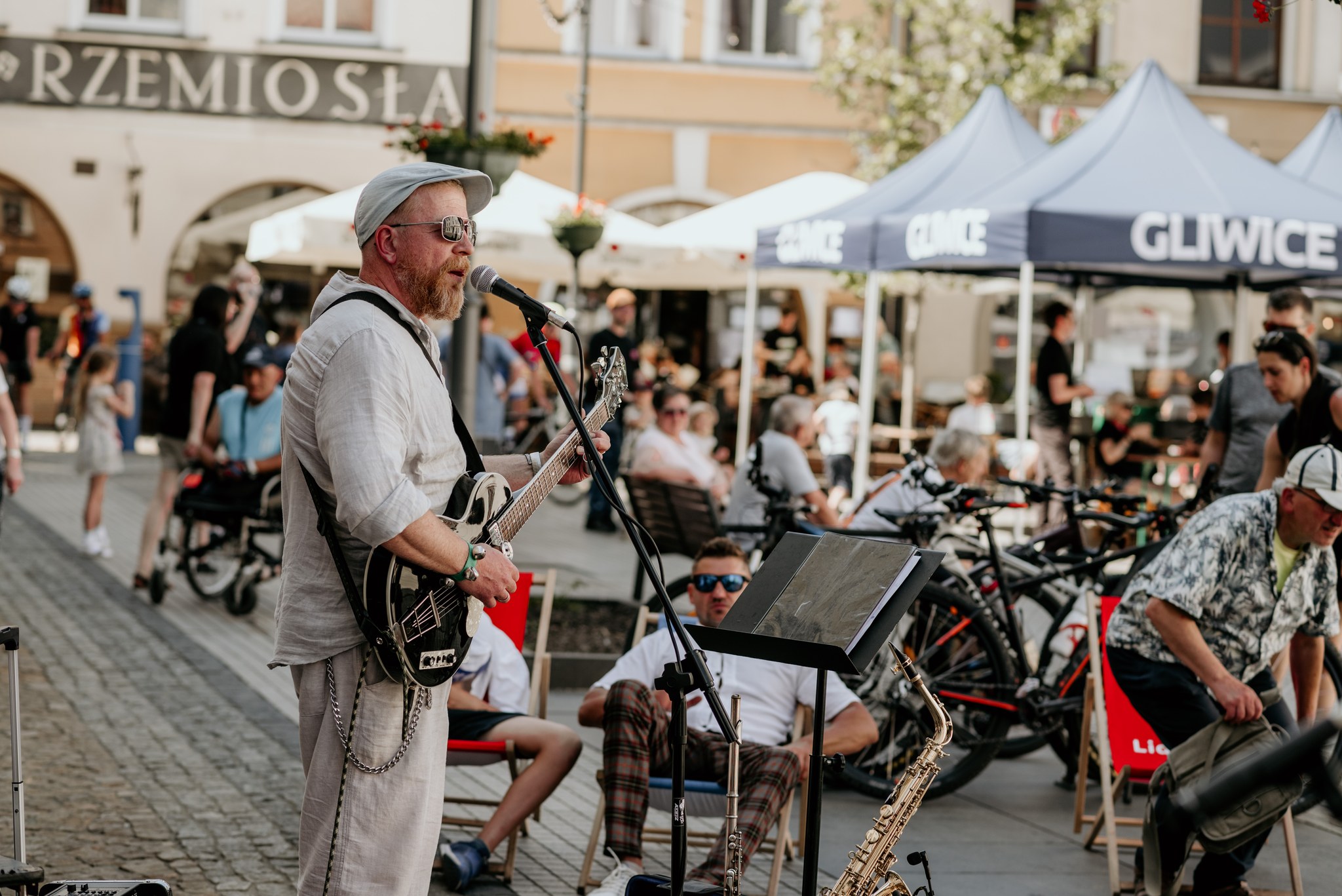 człowiek gra na gitarze, inni ludzie się patrzą 