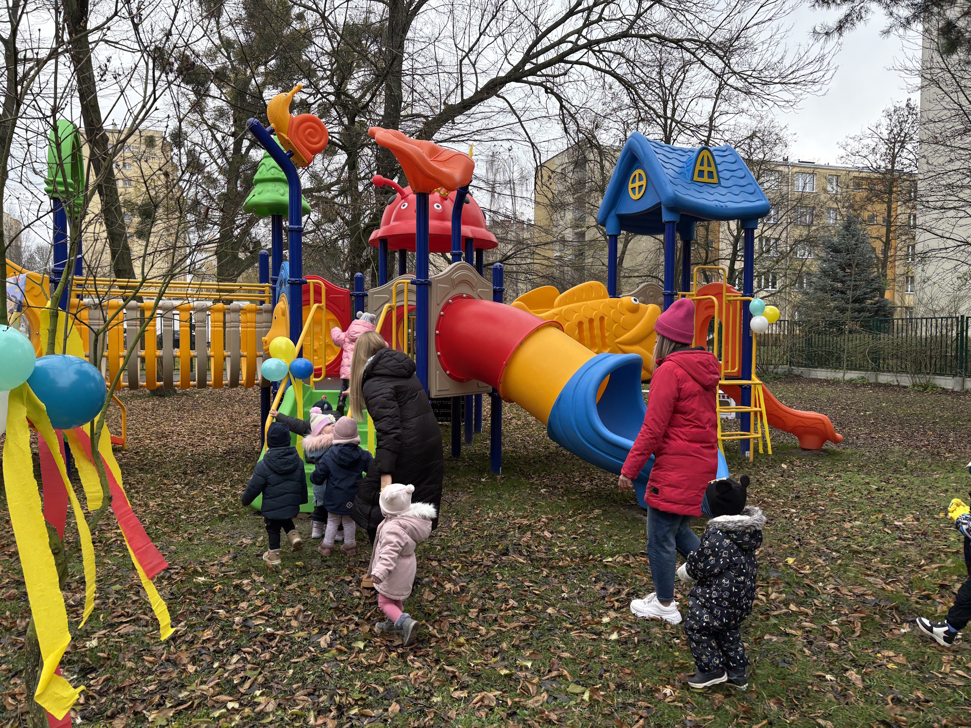 dzieci w kurtkach i czapkach na kolorowym placu zabaw