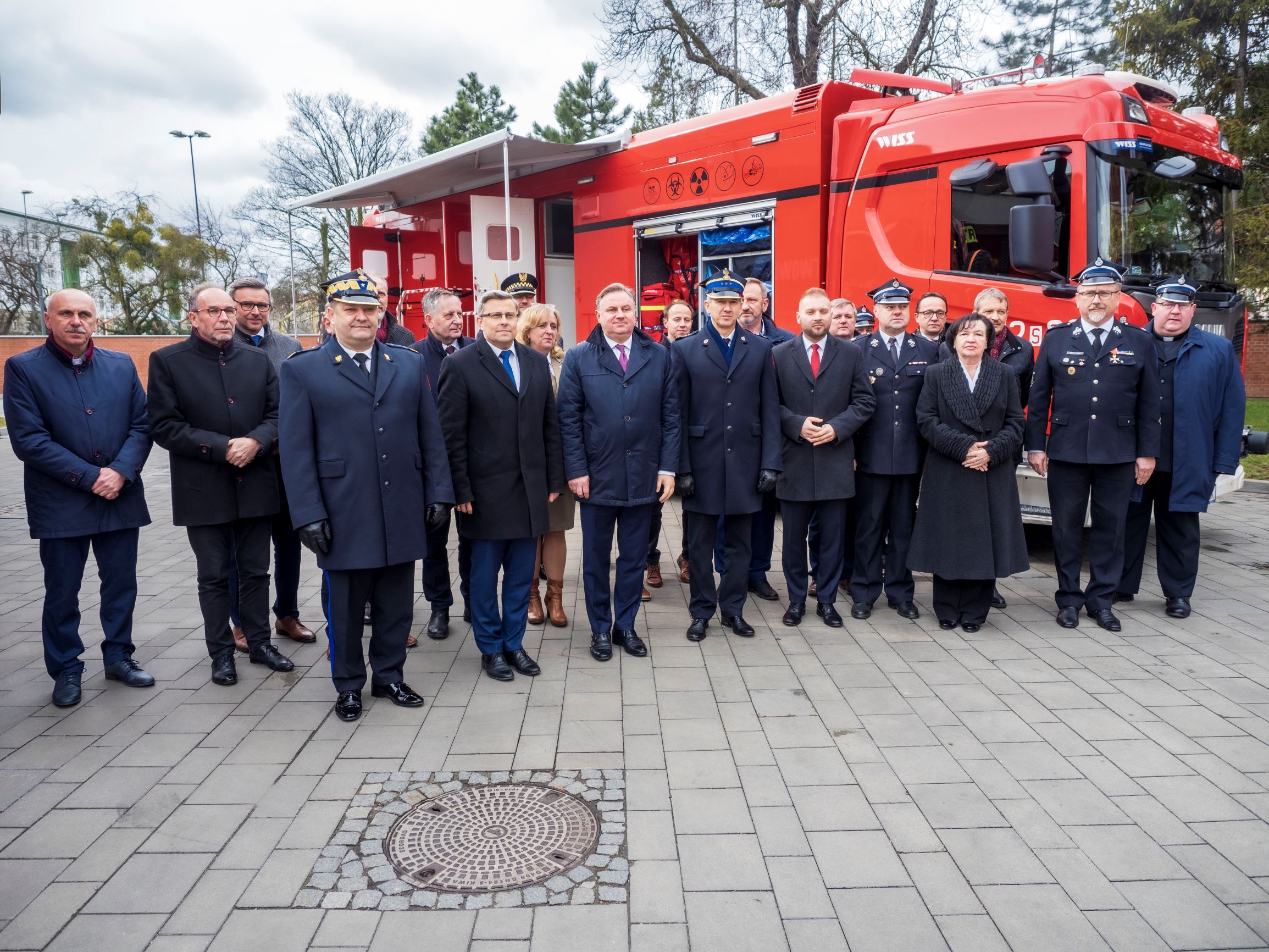 Goście uroczystości przed wozem strażackim