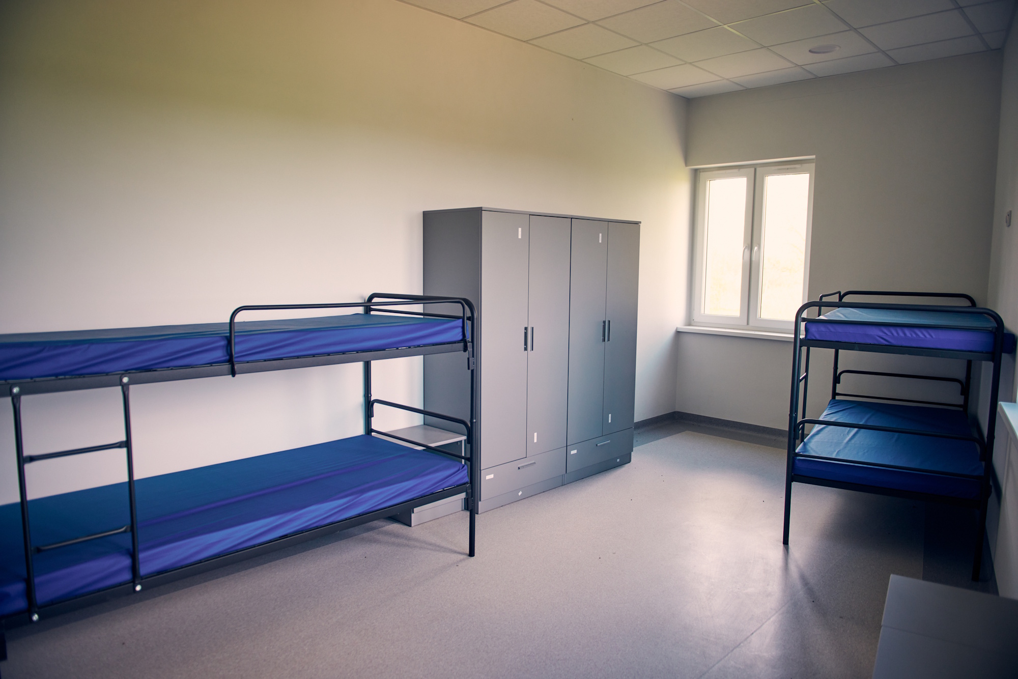 sala w schronisku, łóżka piętrowe z granatowymi prześcieradłami