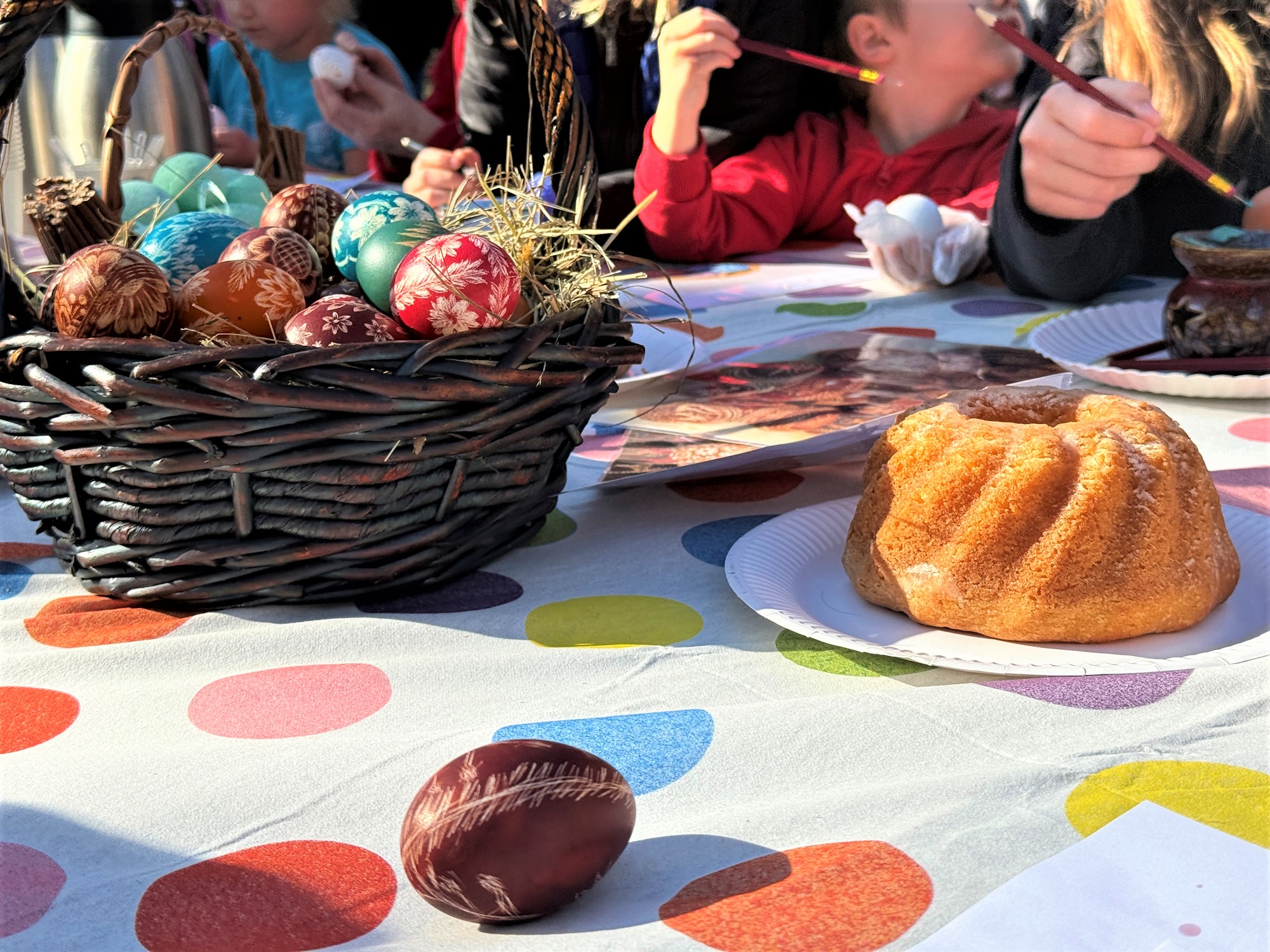Fot. K.Róg/UM Gliwice babka na stole i dziecięcej ręce, w koszyku kolorowe pisanki