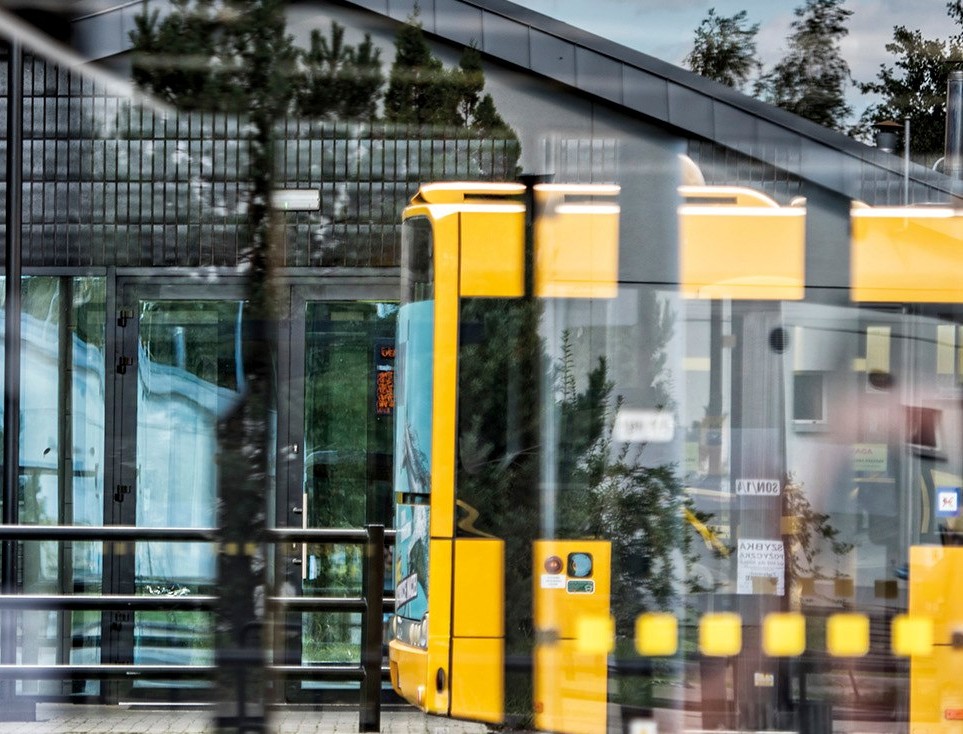 część autobusu na tle szyby przystanku 