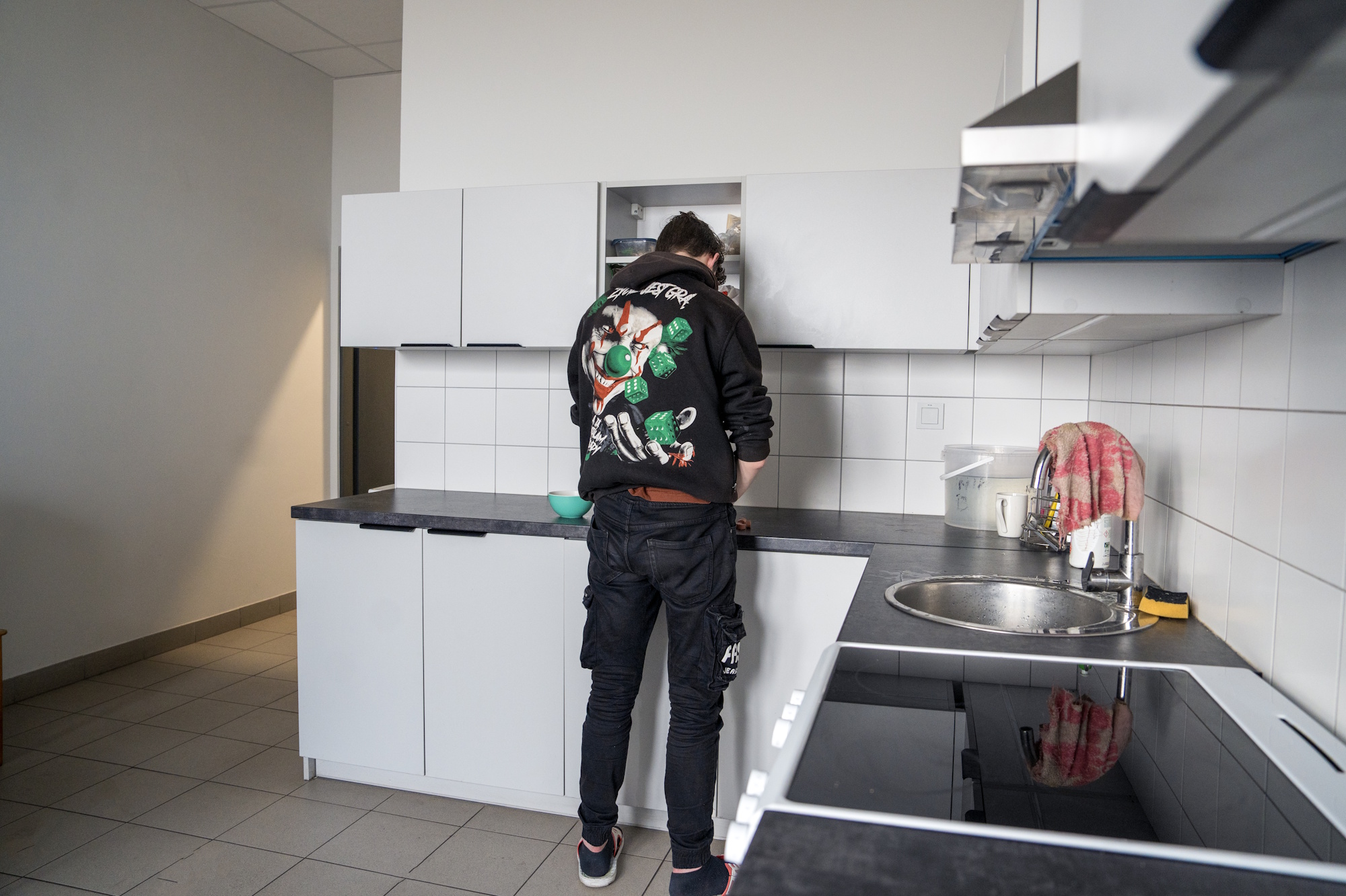 młody człowiek w kolorowej bluzie przy blacie kuchennym