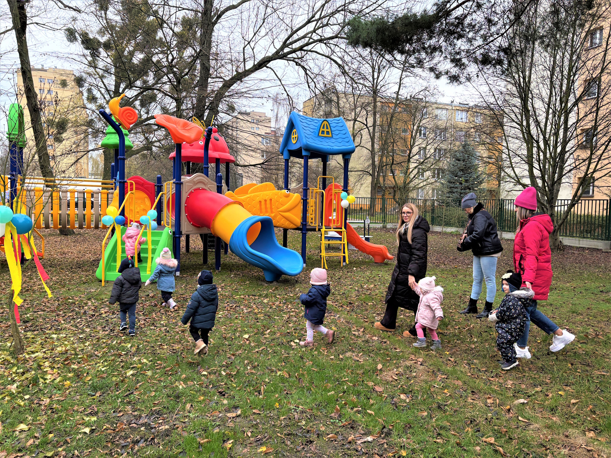 dzieci w kurtkach i czapkach na kolorowym placu zabaw
