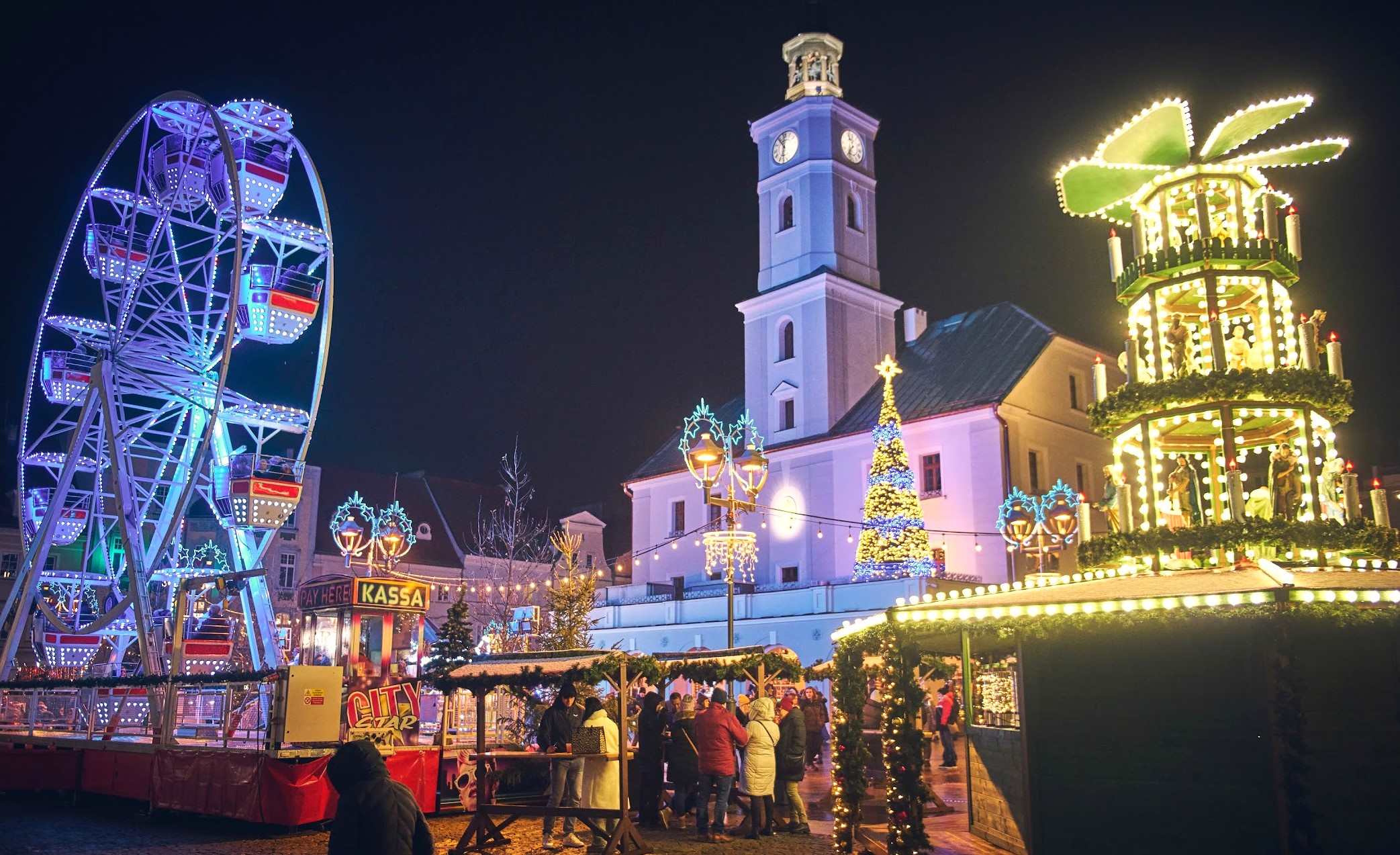 Oświetlony rynek ze straganami ni młyńskim kołem