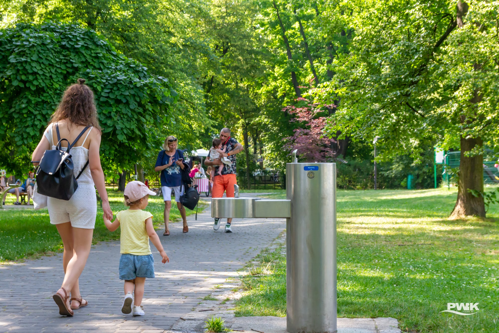 Mama z dzieckiem przechodzący obok zdroju w parku Chopina