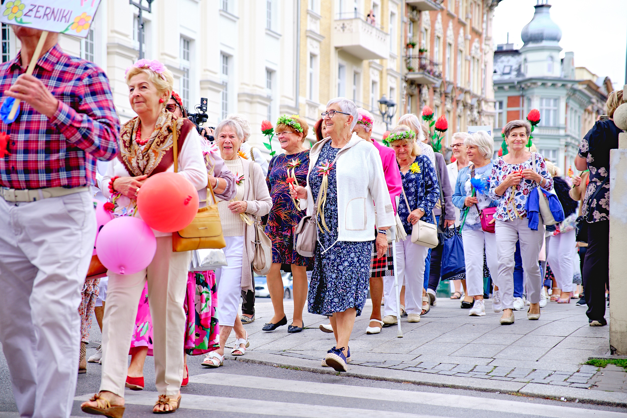 Seniorzy idący w barwnym pochodzie ulicą Zwycięstwa