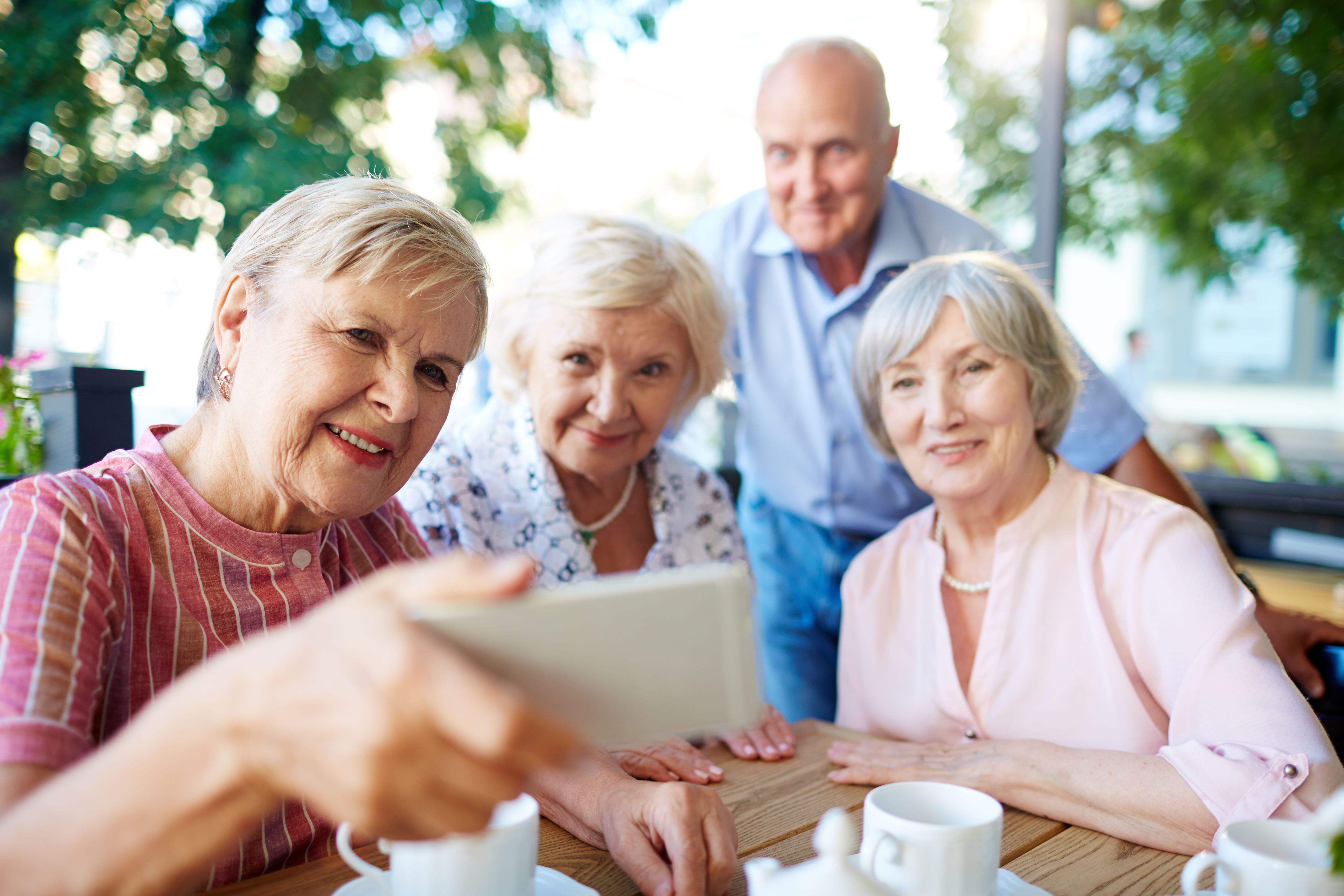 Grupa seniorów patrząca wspólnie w ekran smartphona