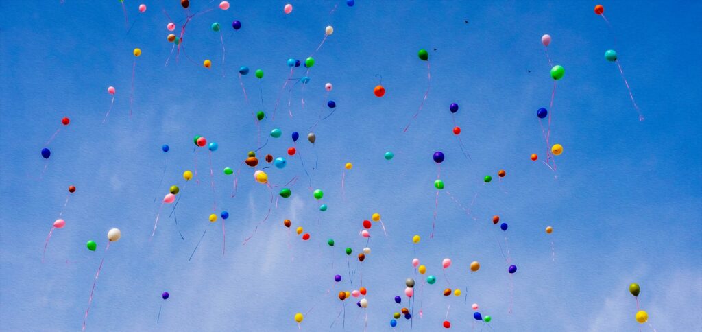 Kolorowe balony lecące na tle nieba